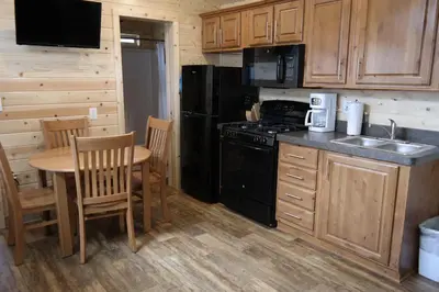 a kitchen with a table and a stove and refrigerator at Pio Pico Camping Resort Cottage 4 in Jamul