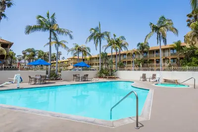 a pool at the resort with tables and chairs and palm trees at Wyndham Garden San Diego in San Diego