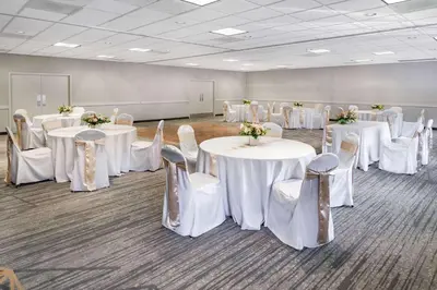 a room with white tables and chairs with flowers on them at Wyndham Garden San Diego in San Diego