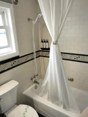 a bathroom with a toilet and a tub with a shower curtain at Cherokee Lodge in San Diego