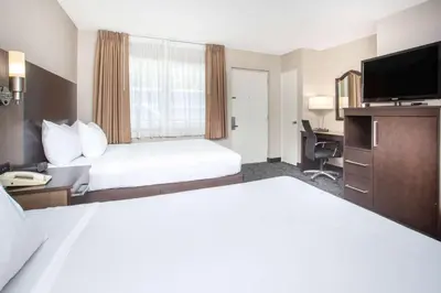 a hotel room with two beds and a flat screen tv at Baymont by Wyndham San Diego Downtown in San Diego