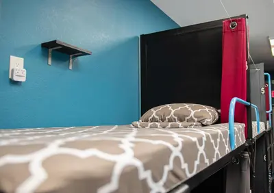 a bed with a black headboard and blue walls at California Dreams Hostel - Pacific Beach in San Diego