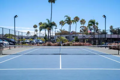 a tennis net on a tennis court with palm trees at San Clemente Inn in San Clemente