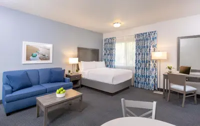 a hotel room with a bed and a blue couch at Beachfront Inn and Suites at Dana Point in Capistrano Beach