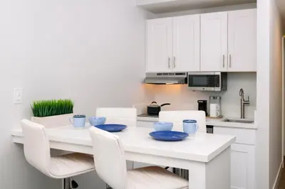 a white kitchen with a white table and white chairs at Beachfront Inn and Suites at Dana Point in Capistrano Beach