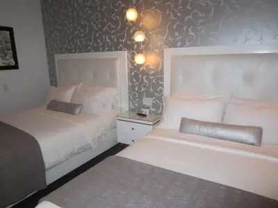 a bedroom with two beds and a night stand with a bedskirts at La Pensione Hotel in San Diego