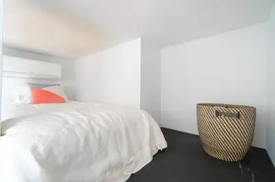 a white bedroom with a bed and a suitcase at Modern Beach Home Steps To The Sand in San Diego