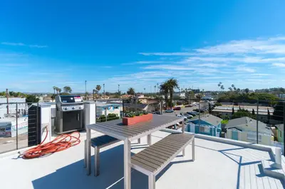 a balcony with a table and bench on a roof at Modern Beach Home Steps To The Sand in San Diego