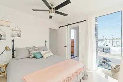 a bedroom with a bed with a ceiling fan at Modern Beach Home Steps To The Sand in San Diego