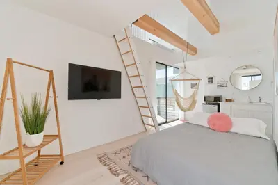 a bedroom with a bed and a ladder and a tv at Modern Beach Home Steps To The Sand in San Diego