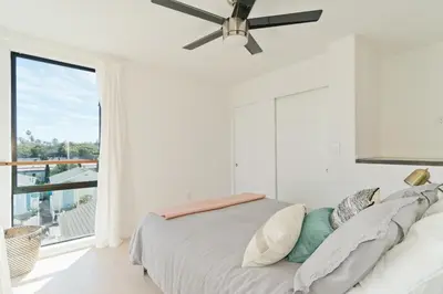 a bedroom with a bed with a ceiling fan at Modern Beach Home Steps To The Sand in San Diego