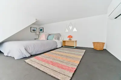 a bedroom with a bed and a rug at Steps to the Beach, Rooftop Deck in San Diego