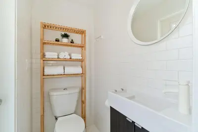 a bathroom with a toilet and a sink and a mirror at Steps to the Beach, Rooftop Deck in San Diego