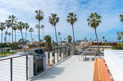 a balcony with a grill and palm trees at Steps to the Beach, Rooftop Deck in San Diego