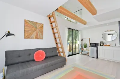 a living room with a couch and a ladder at New Beach House, Steps to Sand in San Diego