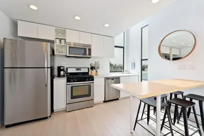 a kitchen with stainless steel appliances and a wooden table at New Beach House, Steps to Sand in San Diego