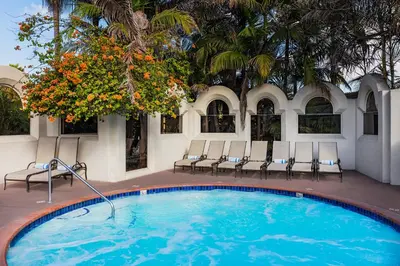 a swimming pool with chairs and a palm tree at Bahia Resort Hotel in San Diego