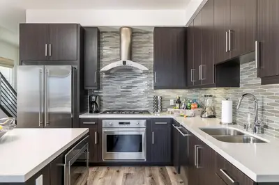 a kitchen with black cabinets and stainless steel appliances at Ocean View 3 Bedrooms Condo, just steps from the park, pier & water! in Imperial Beach