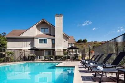 a swimming pool with lounge chairs and a house at Residence Inn San Diego La Jolla in San Diego