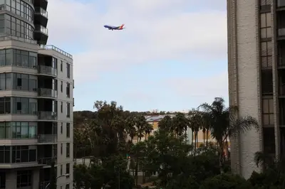 a plane flying in the sky over some buildings at Hotel Ash&9th in San Diego
