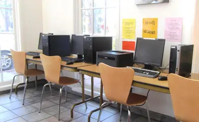 a row of computer monitors on a table with chairs at Motel 6 Hemet in Hemet
