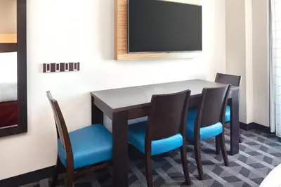 a dining room table with four chairs and a flat screen tv at TownePlace Suites by Marriott San Diego Downtown in San Diego