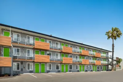 a large apartment building with green windows and a palm tree at SureStay Hotel by Best Western San Diego Pacific Beach in San Diego