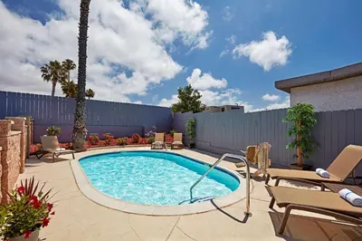 a swimming pool in a patio with chairs and a fence at SureStay Hotel by Best Western San Diego Pacific Beach in San Diego