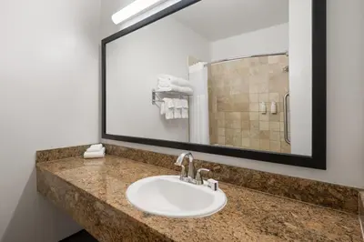 a bathroom with a sink and a large mirror at Ramada Suites by Wyndham San Diego Hotel Circle Area in San Diego