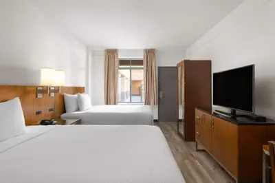 a hotel room with two beds and a flat screen tv at Ramada Suites by Wyndham San Diego Hotel Circle Area in San Diego