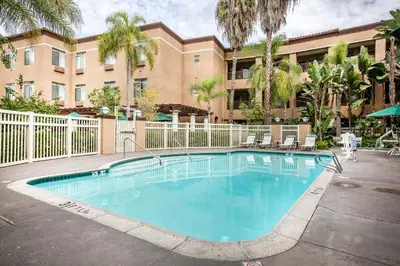 a swimming pool in front of a building at Ramada Suites by Wyndham San Diego Hotel Circle Area in San Diego