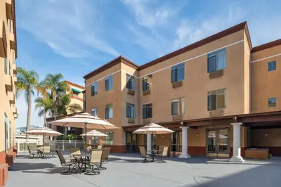 a hotel with tables and chairs and umbrellas at Ramada Suites by Wyndham San Diego Hotel Circle Area in San Diego
