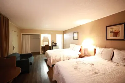 a hotel room with two beds and a chair at Royal Inn and Suites in Hemet