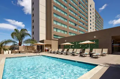 a swimming pool with chairs and a building at Hilton San Diego Mission Valley in San Diego