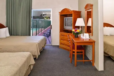 a hotel room with two beds and a desk with a television at Americas Best Value Inn Loma Lodge in San Diego