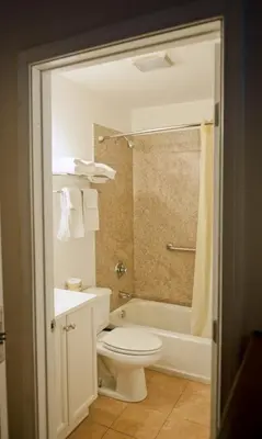 a bathroom with a toilet and a tub and a sink at Downtown San Diego Lodge in San Diego