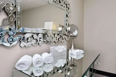 a bathroom with a mirror and towels on a shelf at voco Laguna Hills by IHG in Laguna Hills