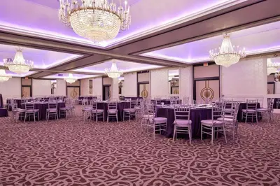 a banquet hall with tables and chairs and chandeliers at voco Laguna Hills by IHG in Laguna Hills