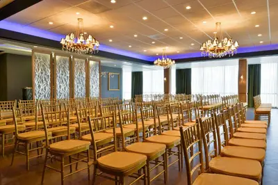 a room with rows of tables and chairs at voco Laguna Hills by IHG in Laguna Hills
