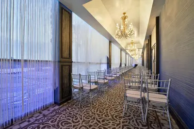 a row of chairs lined up in a corridor with a room with windows at voco Laguna Hills by IHG in Laguna Hills