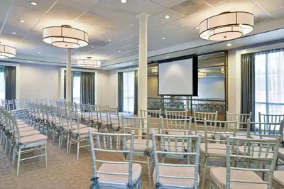 a conference room with rows of chairs and a screen at voco Laguna Hills by IHG in Laguna Hills