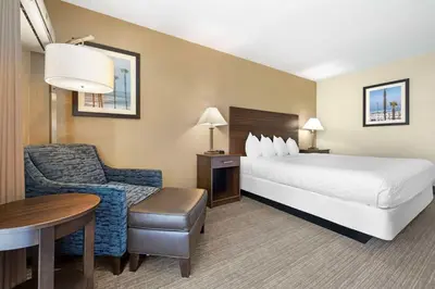 a hotel room with a bed and a chair and a table at Best Western Oceanside Inn in Oceanside
