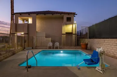 a swimming pool with a blue chair next to a house at Quality Inn Lake Elsinore I-15 in Lake Elsinore