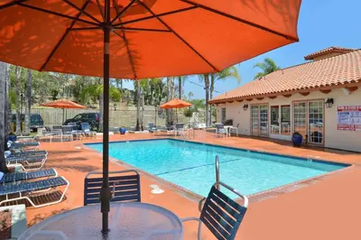 a table with an umbrella next to a swimming pool at Best Western Capistrano Inn in San Juan Capistrano