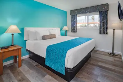 a bedroom with a large bed with a blue wall at Howard Johnson Suites by Wyndham San Diego Chula Vista BayFront in Chula Vista