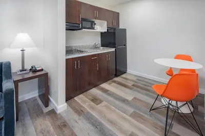 a room with a table and a chair and a kitchen at Howard Johnson Suites by Wyndham San Diego Chula Vista BayFront in Chula Vista
