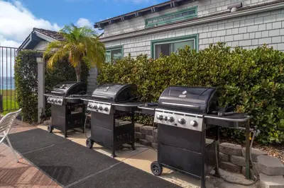 a row of three barbecue stoves in front of a house at Wave Crest Resort in San Diego