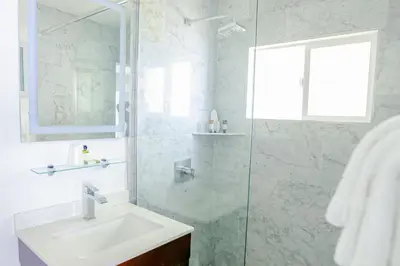 a bathroom with a sink and a glass shower at Capri Laguna on the Beach - A Boutique Hotel in Laguna Beach