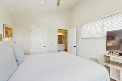 a white bedroom with a bed and a flat screen tv at Villa Del Mar in San Clemente