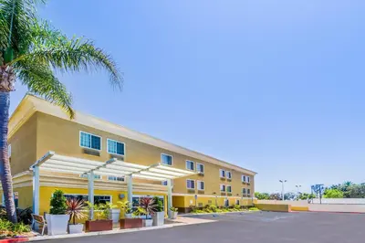 a large yellow building with a palm tree in front of it at GreenTree Inn San Diego Mission Bay in San Diego